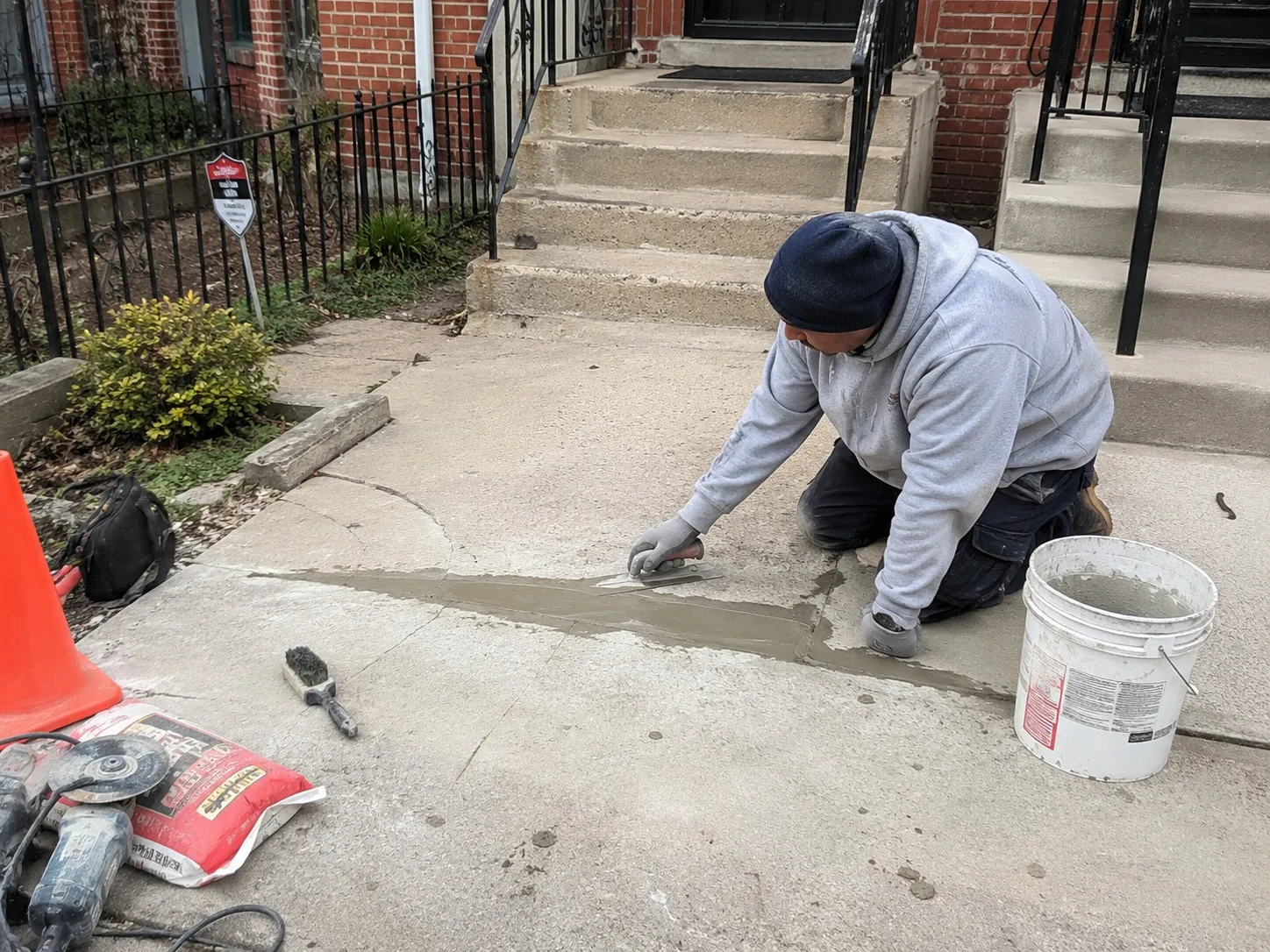 Contractor troweling a repair patch into a cracked concrete walkway outside a Washington DC rowhouse