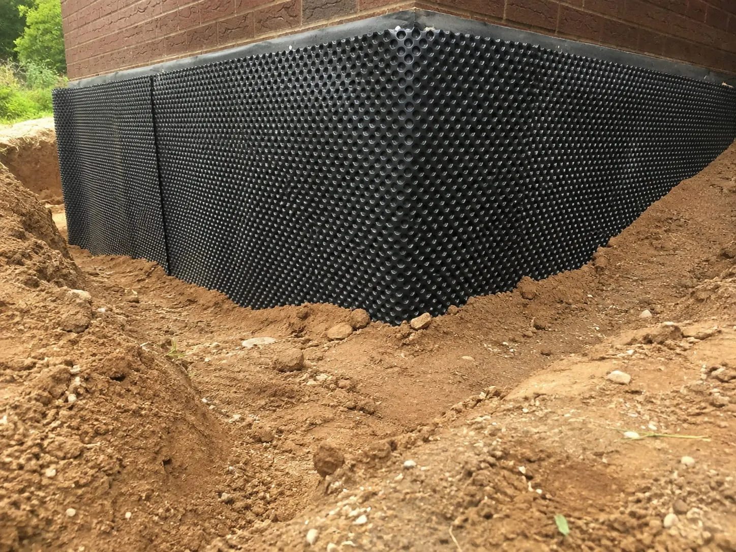 Dimpled damp proofing membrane installed against an excavated Washington DC foundation wall