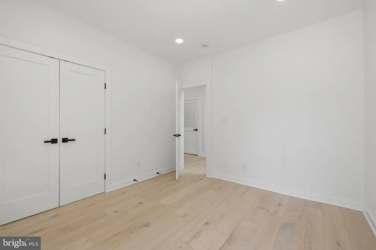 Finished bedroom with fresh plaster, matte black hardware and wide-plank oak flooring