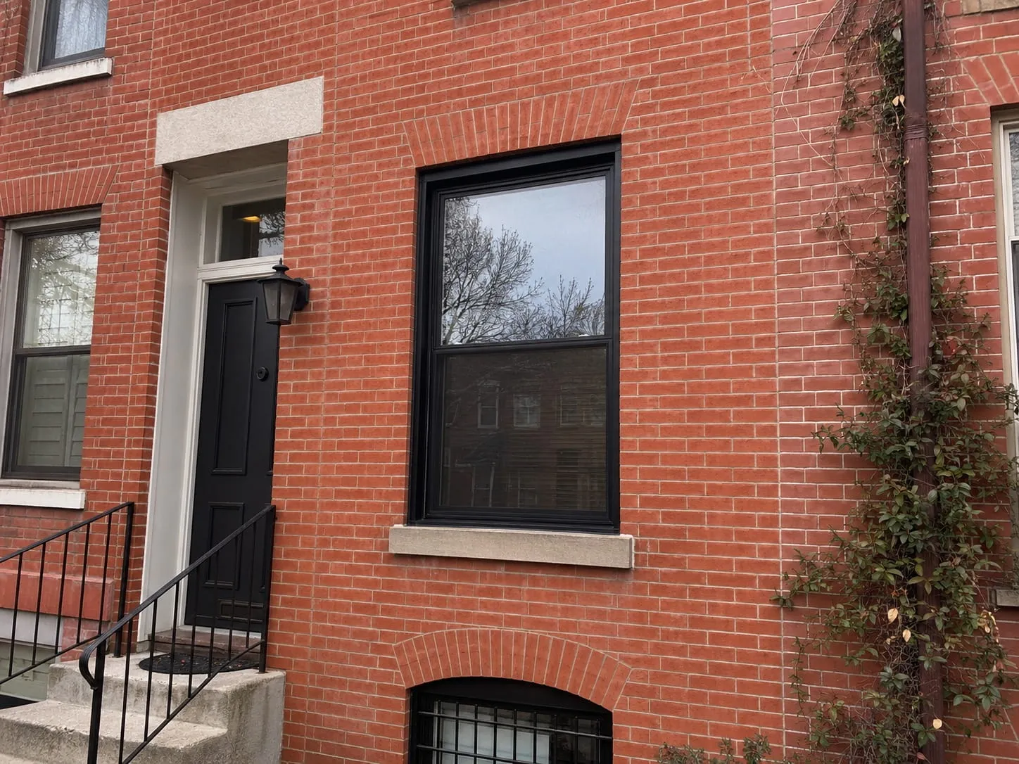 Restored historic rowhouse facade in Washington DC with repointed red brick and a rebuilt brick arch above the window