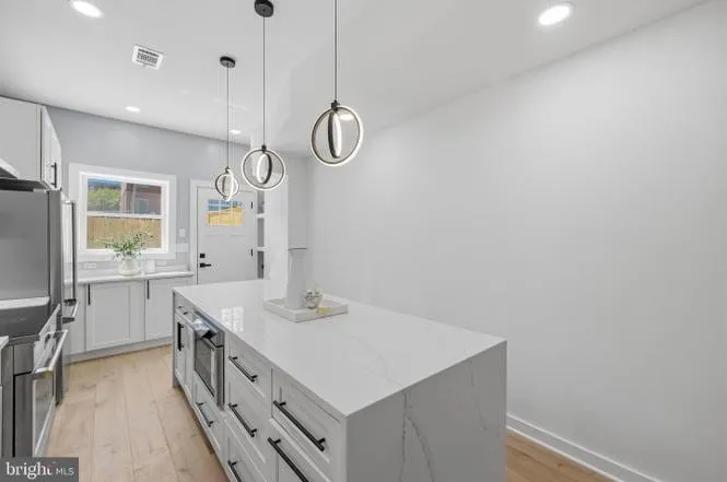 Quartz kitchen island with custom cabinetry and a rear door to the garden