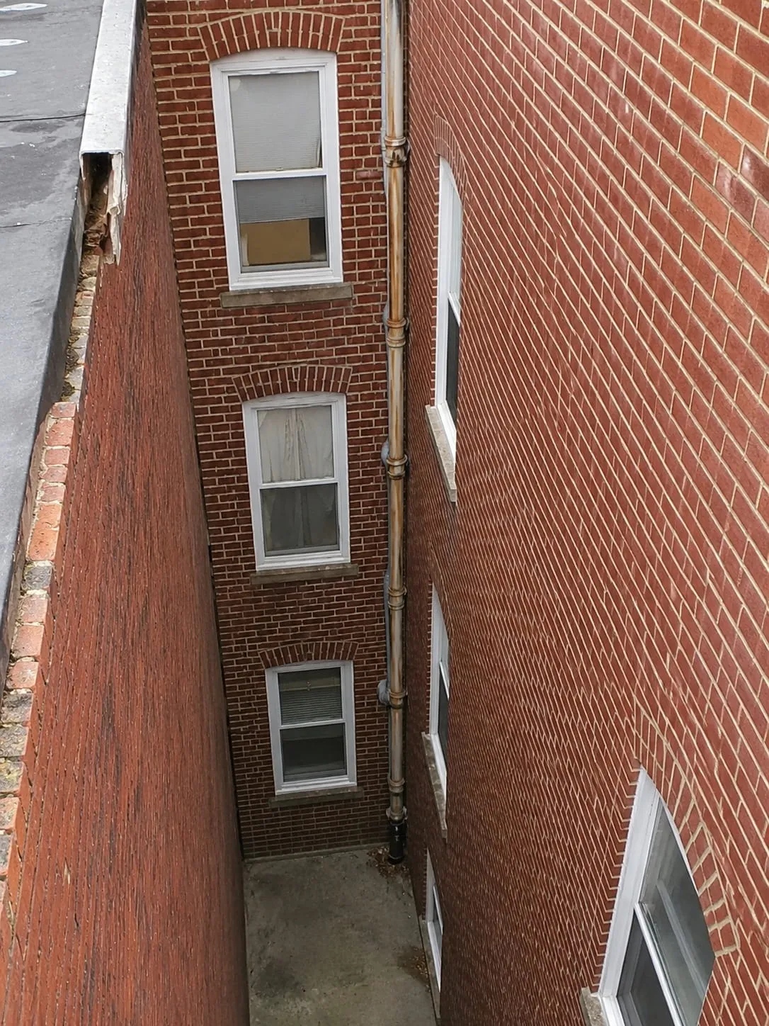 Restored brickwork and repointed mortar joints along a narrow rowhome light well