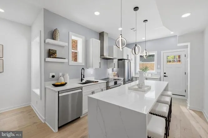 Open-plan kitchen with a quartz waterfall island and pendant lighting