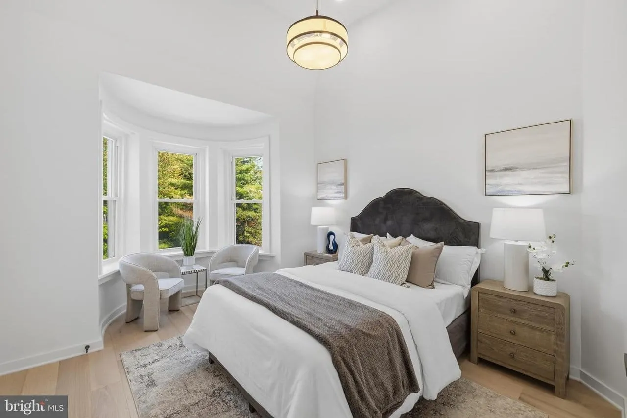 Primary bedroom with a curved bay window and white oak floors in the Woodridge bungalow
