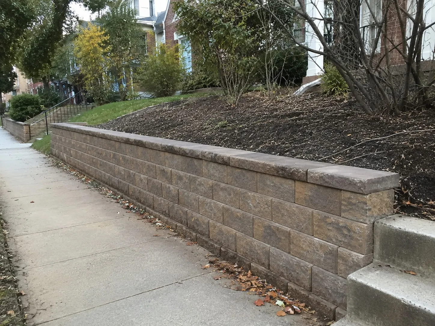 Segmental block retaining wall with a capped top holding back a planted bank along a Washington DC sidewalk