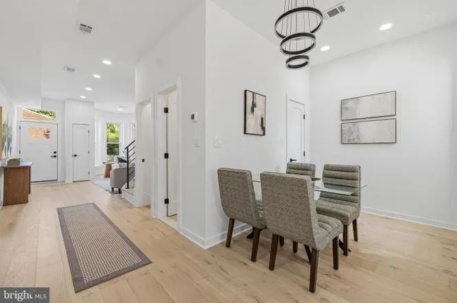 Dining area and entry hall with a sculptural pendant light and open stair beyond