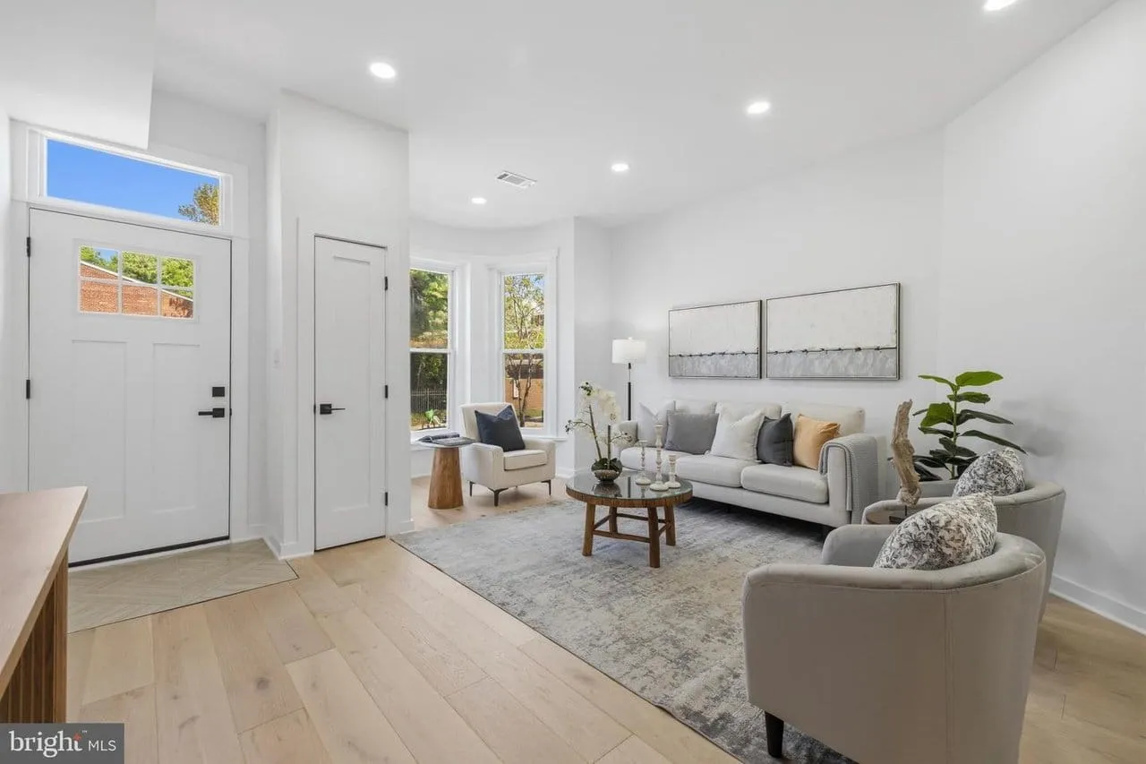 Restored Shaw rowhome living room with a bay window, wide-plank oak floors and a new front door