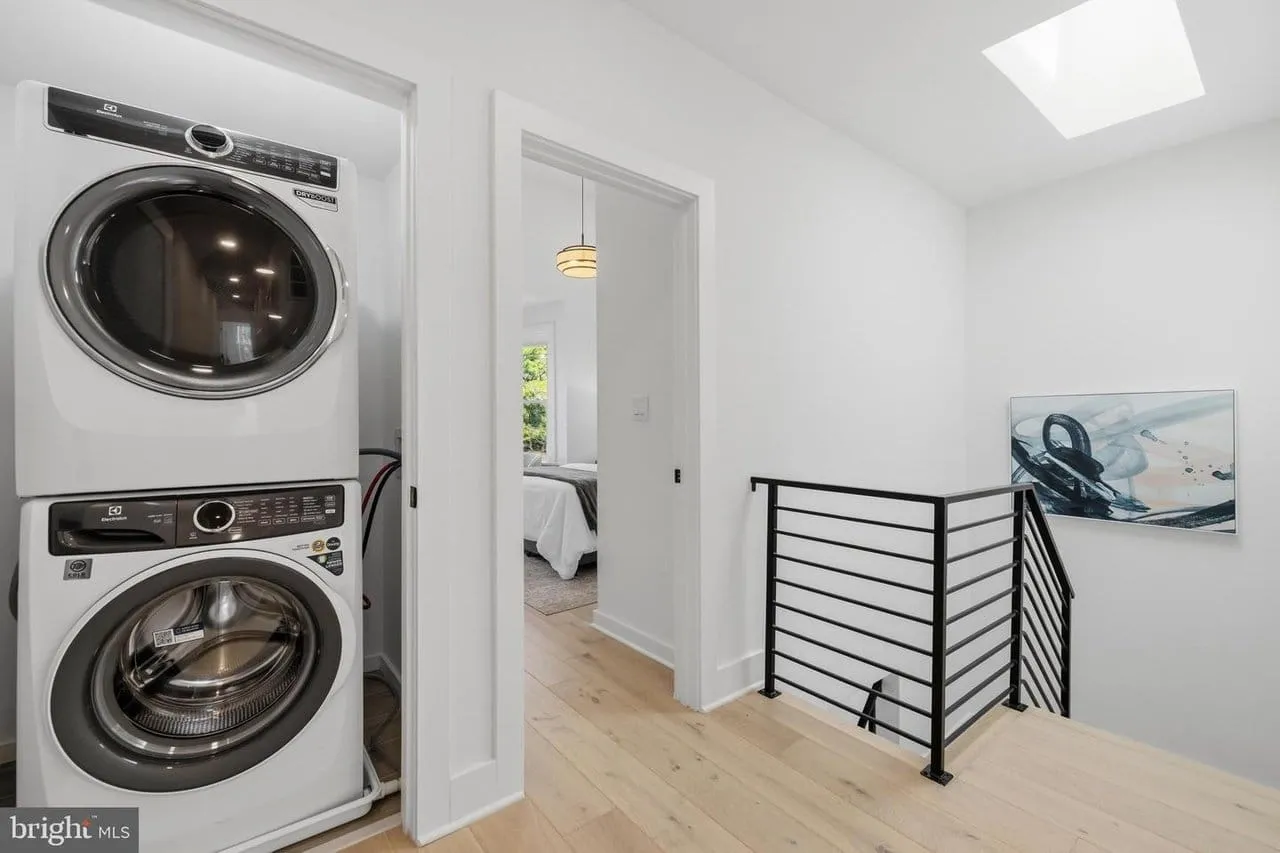 Upper-floor landing with a skylight, black steel railing and a built-in laundry closet