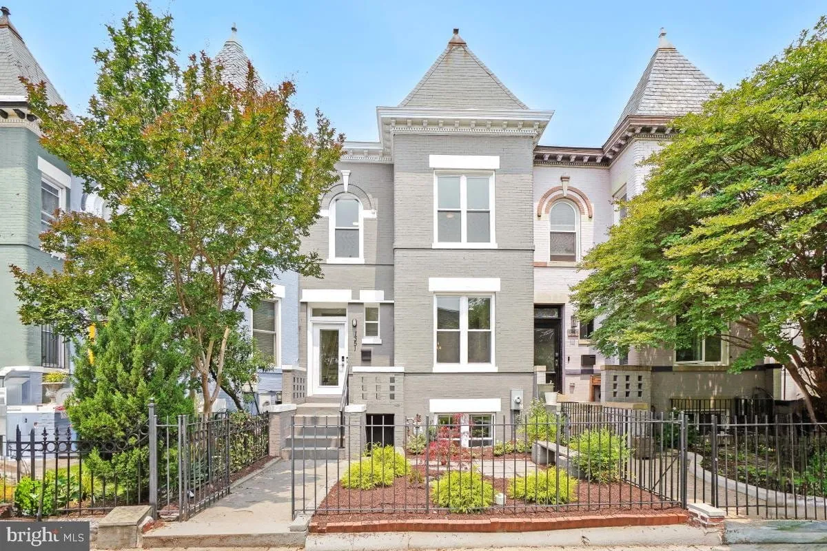 Grey painted bayfront Victorian townhome in Washington DC with a turret roof and iron front fence
