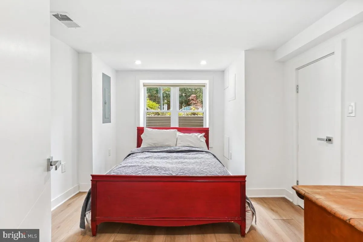 In-law suite bedroom with a red bedframe and a window looking out to the front garden