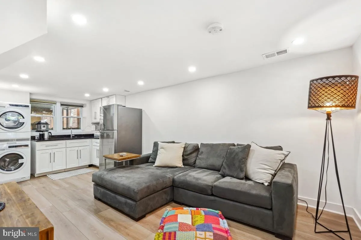 Lower-level in-law suite living area with a kitchenette, stacked laundry and recessed lighting